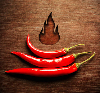 顶部视图背景.三只新鲜的红辣椒是金字塔.木制火焰照片