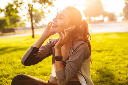 愉快的快乐可爱的图片健身运动妇女在公园户外听音乐用耳机照片