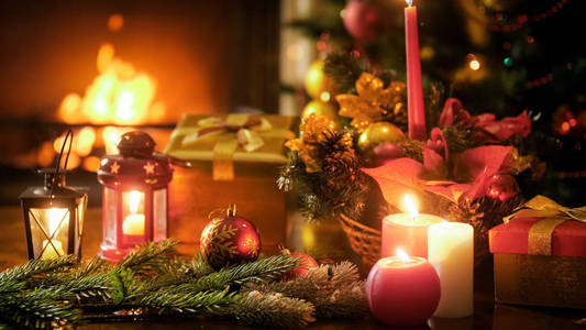 美丽的圣诞节背景与蜡烛和灯笼在木桌上反对燃烧壁炉