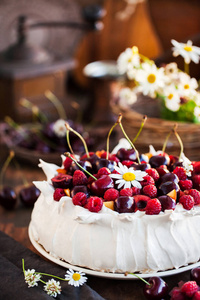 美味的帕夫洛娃酥皮蛋糕, 装饰新鲜的覆盆子和樱桃在乡村背景下