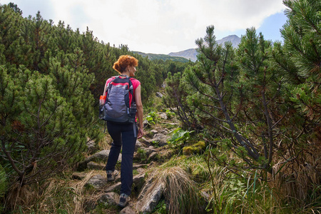 中年妇女与背包徒步旅行在山区的足迹白天