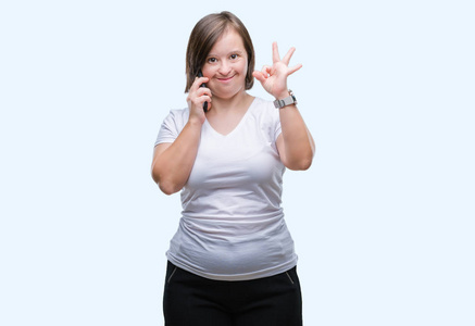 有唐综合症的年轻成年妇女使用智能手机在孤立的背景下做 ok 标志与手指, 优秀的标志