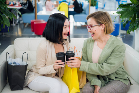 两个年轻女人在购物中心一起喝咖啡休息