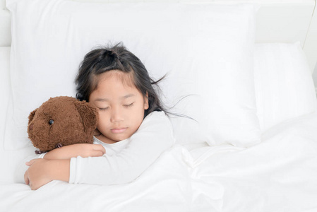 漂亮的小女孩在家里睡觉的时候抱着泰迪熊, 顶着健康的概念休息