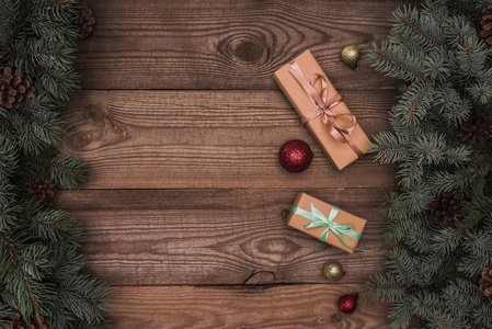 圣诞礼物的顶部风景, 有光泽的华而不实和针叶树的树枝与松树锥在木质背景下