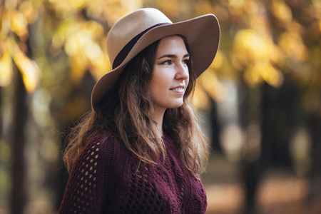 秋季公园户外的年轻女子的肖像穿着舒适的毛衣和帽子。温暖的阳光天气。秋天概念。复制空间