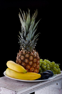 木制的桌子上的水果碗。在黑色背景上的水果。维塔