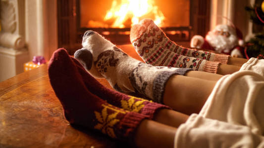 家庭穿着羊毛袜子温暖壁炉的特写图像
