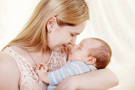 美丽的年轻母亲亲吻和拥抱她刚出生的男婴。母性观念。幸福家庭理念