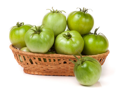 未成熟的绿色蕃茄在白色背景上孤立的柳条篮子里
