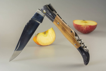 折叠式旅行刀和半切苹果在灰色桌上