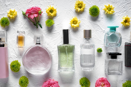 在白色纹理背景上的平躺组成与瓶香水和花朵