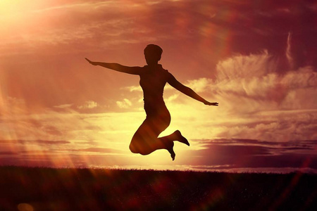 剪影的年轻女子跳跃户外对日落天空, 幸福的概念