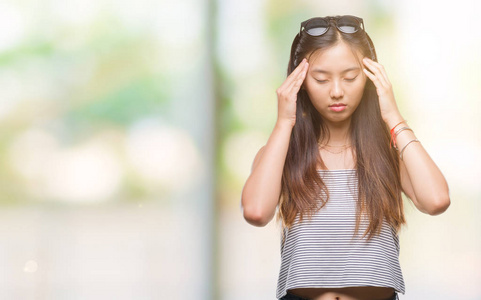 年轻的亚洲妇女戴着太阳镜在孤立的背景下, 手在头部疼痛的头部, 因为压力。患偏头痛
