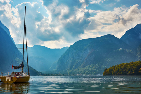 哈尔施塔特湖的景色, 有游艇和山脉, 背景为森林, 蓝天下有戏剧性的云层。奥地利在欧洲