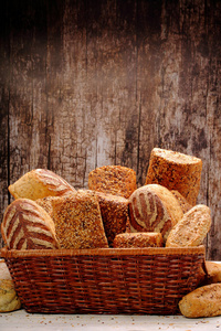 不同类型的面包和包子在一个金属篮子的木质背景和空白的文本