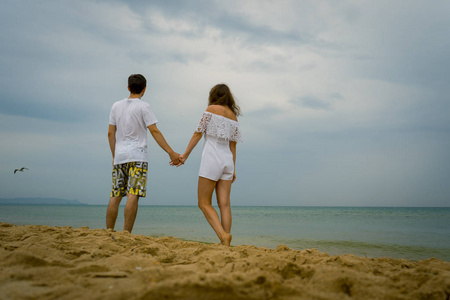 幸福的情侣漫步在海滩或海洋。爱的情侣沿着海岸散步