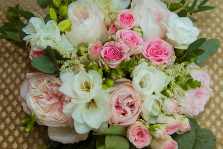 白金结婚戒指。新娘和新郎的两个白金戒指和一束粉红色的玫瑰和白色的花朵