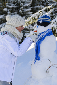 快乐微笑的少女，玩一个雪人在白雪皑皑的胜利