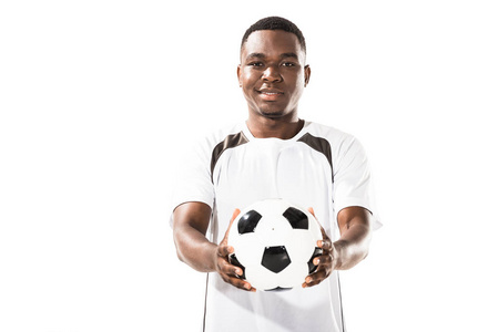 英俊快乐的年轻非洲裔美国运动员举行足球和微笑着在白色的相机隔离