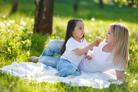 愉快的妈妈和女儿花时间在绿色公园和吃冰淇淋
