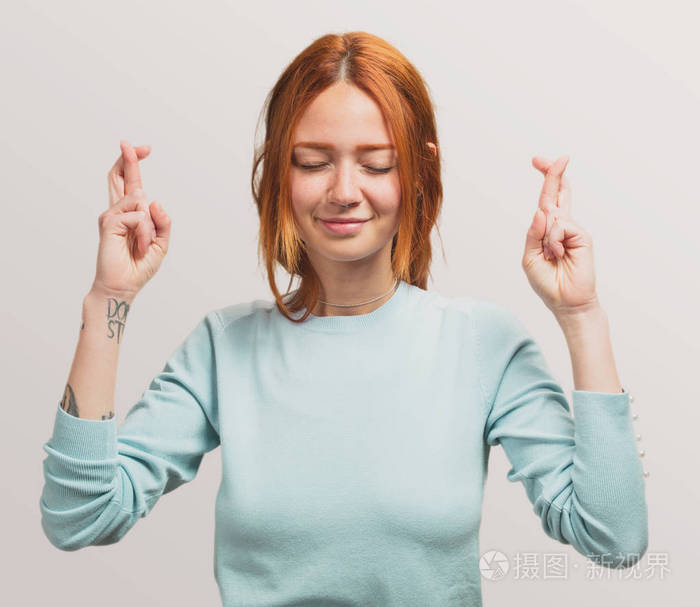 一个漂亮的红发女孩的肖像做一个幸运的手势
