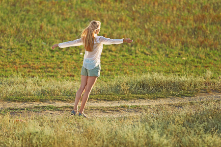 阳光明媚的日子里走在田野上的年轻女子