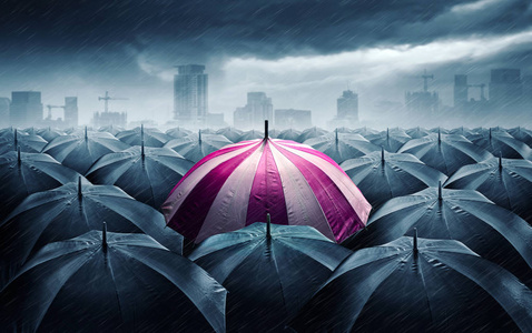 粉红色和白色的伞与黑暗的暴风雨云。成功的概念