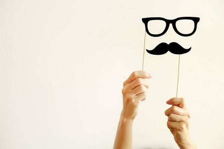 Movember 概念。11月是男性健康问题和前列腺癌意识的月份。年轻妇女拿着纸胡子和眼镜在棍子用两只手。背景, 特写, 复制空