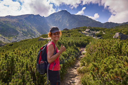 中年妇女与背包徒步旅行在山区的足迹白天