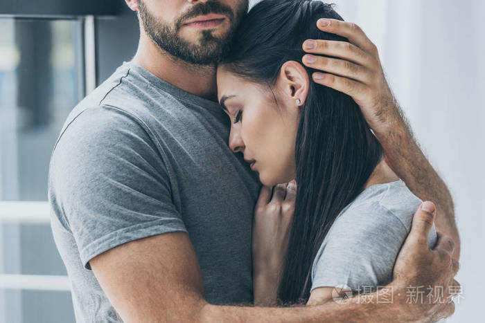 被裁剪的胡子男子拥抱和支持年轻的悲伤的女人拍摄