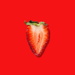 红色背景的新鲜成熟草莓的一半
