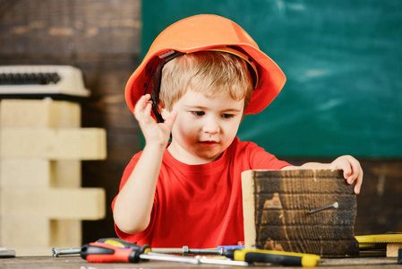 儿童在头盔可爱的发挥建设者或维修, 修理或就要手工制作。就要手工制作概念。在忙碌的脸上蹒跚学步的孩子在车间里玩耍。小男孩扮演杂工