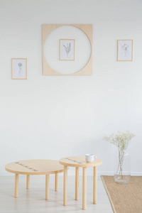 木桌和花在白色极小的客厅内部与海报和地毯。真实照片