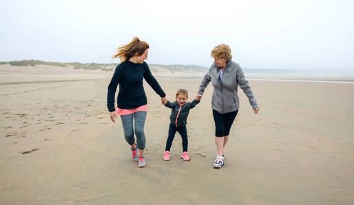 三代女性秋季在海滩上奔跑