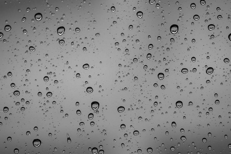雨落在外面汽车镜子窗口玻璃表面以多云背景。多云背景下的雨滴自然图案。场浅景深