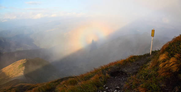 从草地上, 橙色的草地打开了高山的全景, 蓝天白云和一个布罗肯幽灵在雾中的秋天一天