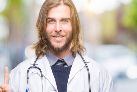 长头发的年轻英俊的男性医生以模糊多彩的背景