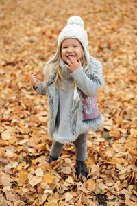 女孩在一顶帽，秋天叶站在秋天公园在晚上