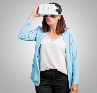 中年妇女兴奋和娱乐, 玩虚拟现实眼镜, 探索一个梦幻世界, 试图触摸的东西