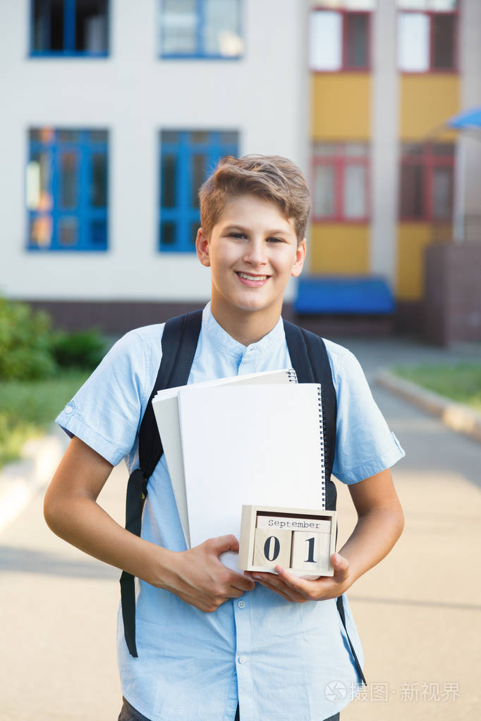 可爱的, 漂亮的, 年轻的11岁的男孩穿着蓝色衬衣站在他的学校前面的