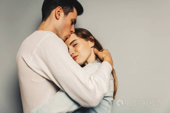 女孩在微笑, 而她的男友亲吻她的额头