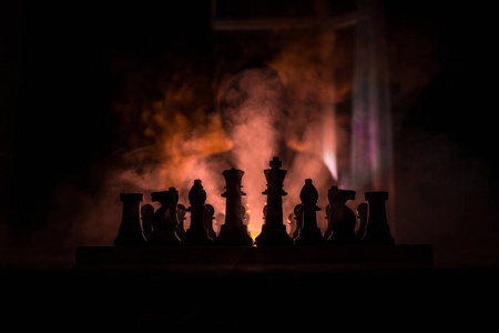 人在下棋。一个人在棋盘上的可怕模糊剪影与国际象棋数字。深色色调的雾背景。选择性对焦。恐怖概念