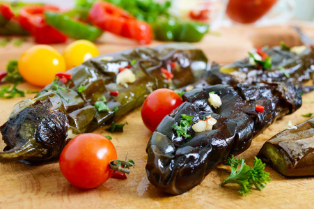 美味的烤蔬菜茄子配香草, 大蒜, 西红柿在木板上