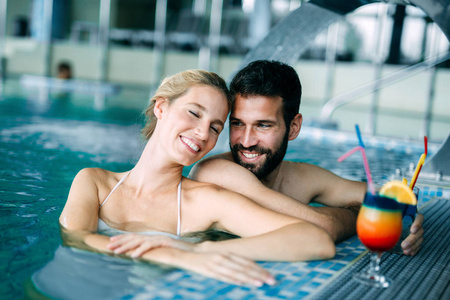快乐迷人情侣在水疗游泳池放松身心