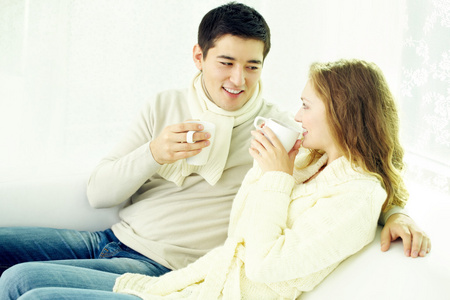 坐在家里喝茶对年轻的夫妇照片