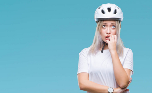 年轻的金发女子穿着自行车安全头盔在孤立的背景下