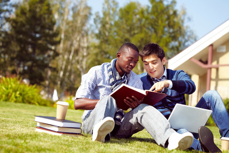 两个学生坐在校园的草地上