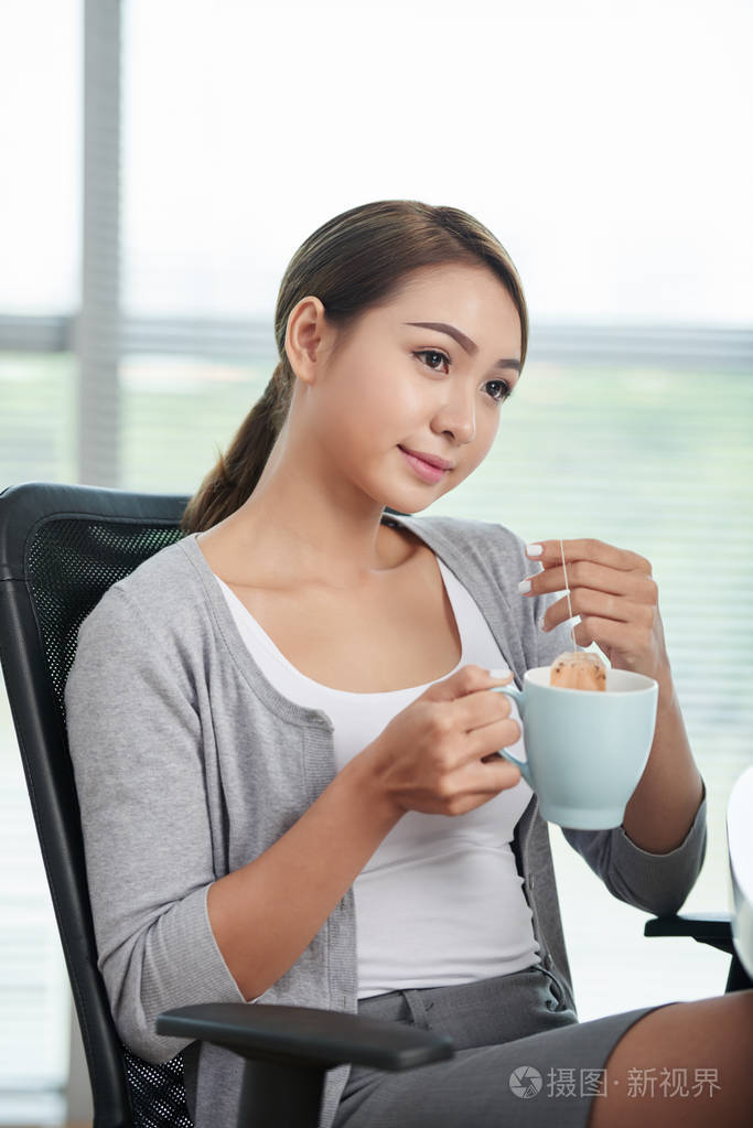 沉思女企业家在工作场所喝茶的画像