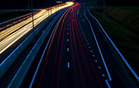 夜晚, 汽车在弯曲的公路上照明。夜间交通路线。运动模糊。夜城市路与交通车灯运动。市容.用车辆运动模糊照亮道路